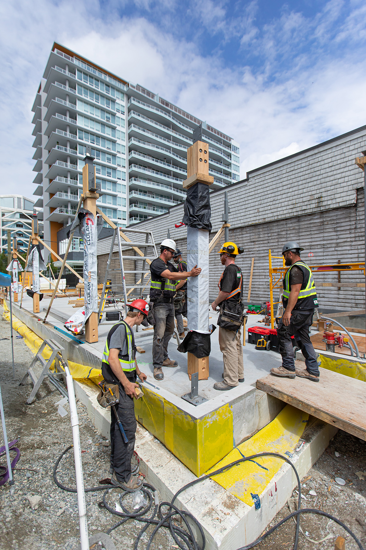 Construction crew members place vertical wood post in place
