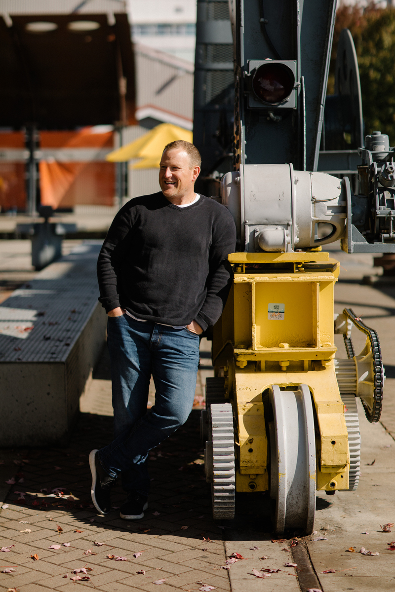Naikoon President Joe Geluch stands in front of large industrial equipment